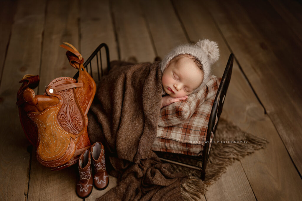 Little cowboy: Newborn sleeping soundly on a little bed. 