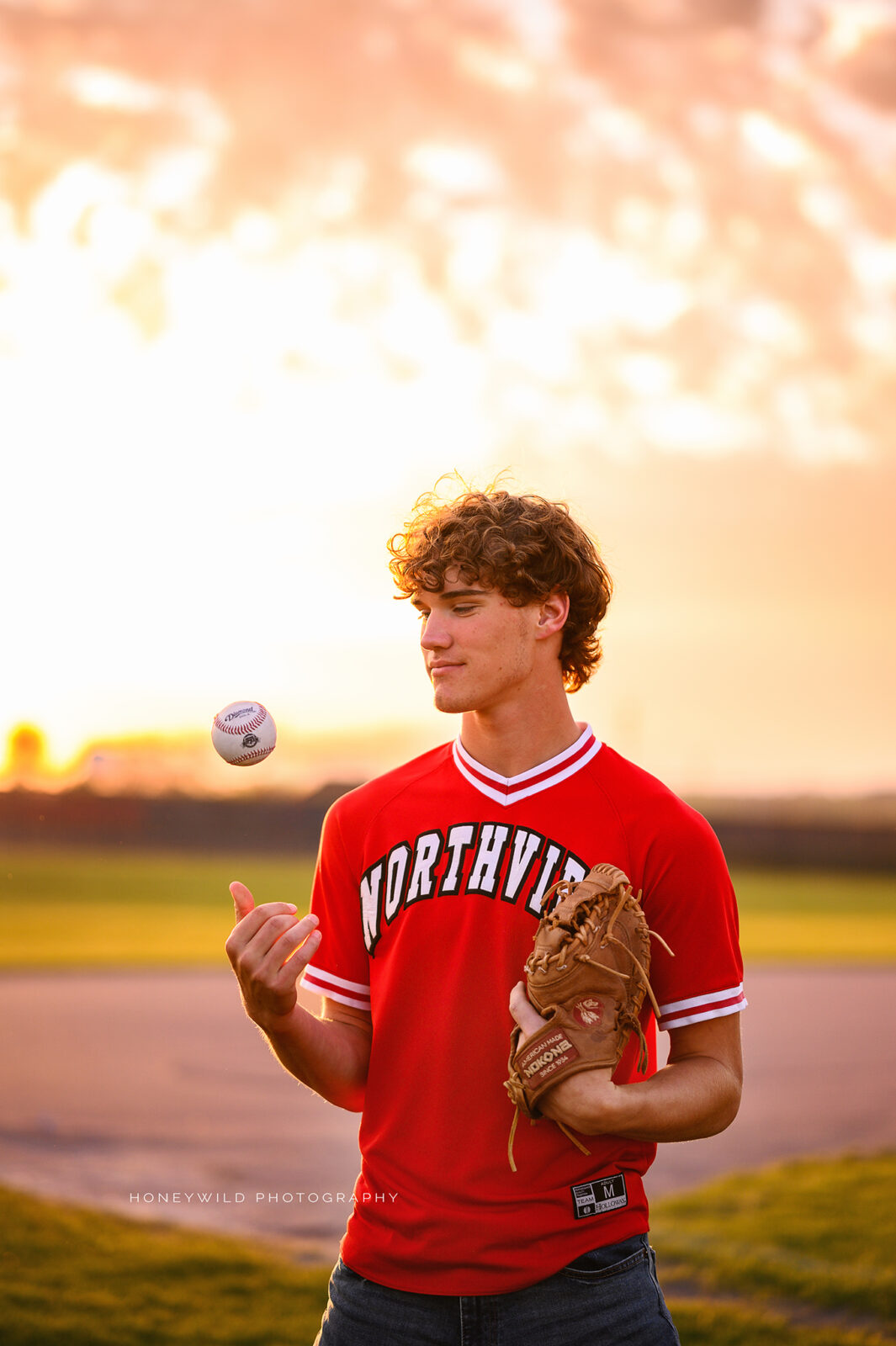 grand rapids senior boy throwing a baseball up in the air