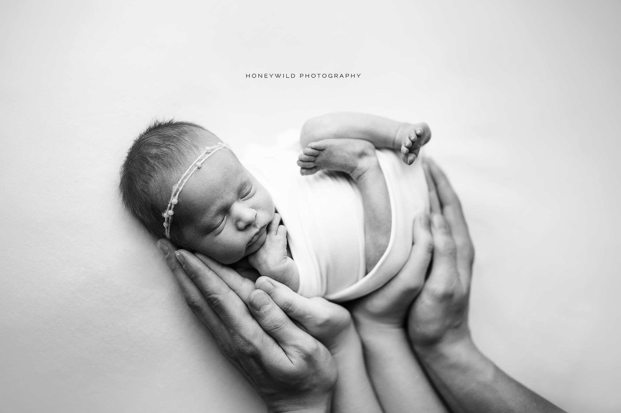 Newborn baby resting safely in mom and and dad's hands 
