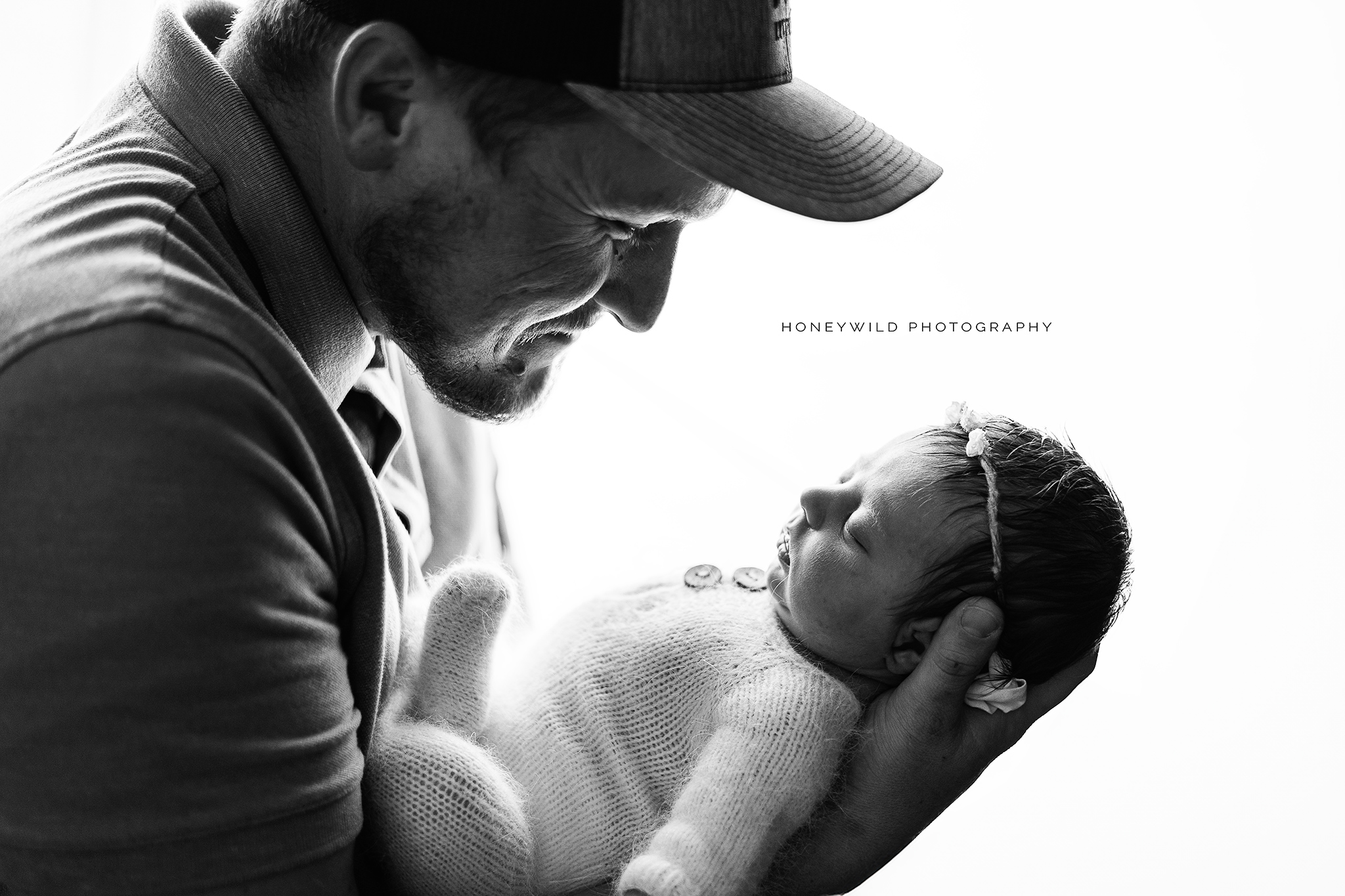 classic black and white newborn images of dad looking lovingly at his new baby taken by one of the best newborn photographers in grand rapids