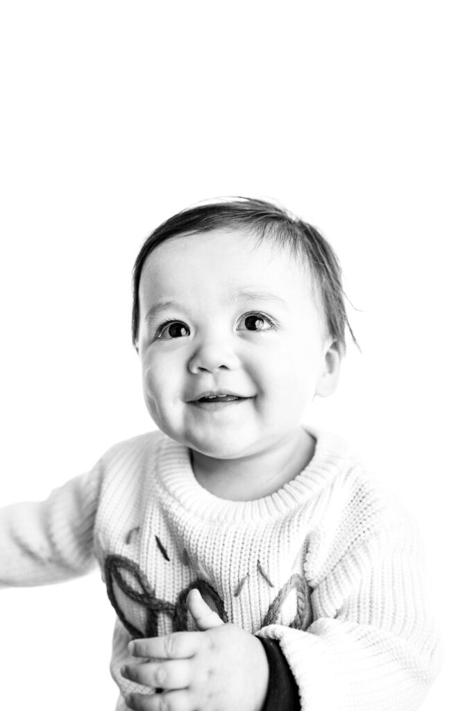 Timeless black-and-white portrait of a smiling baby boy, showcasing his bright eyes and adorable dimples, captured by Grand Rapids newborn photographer