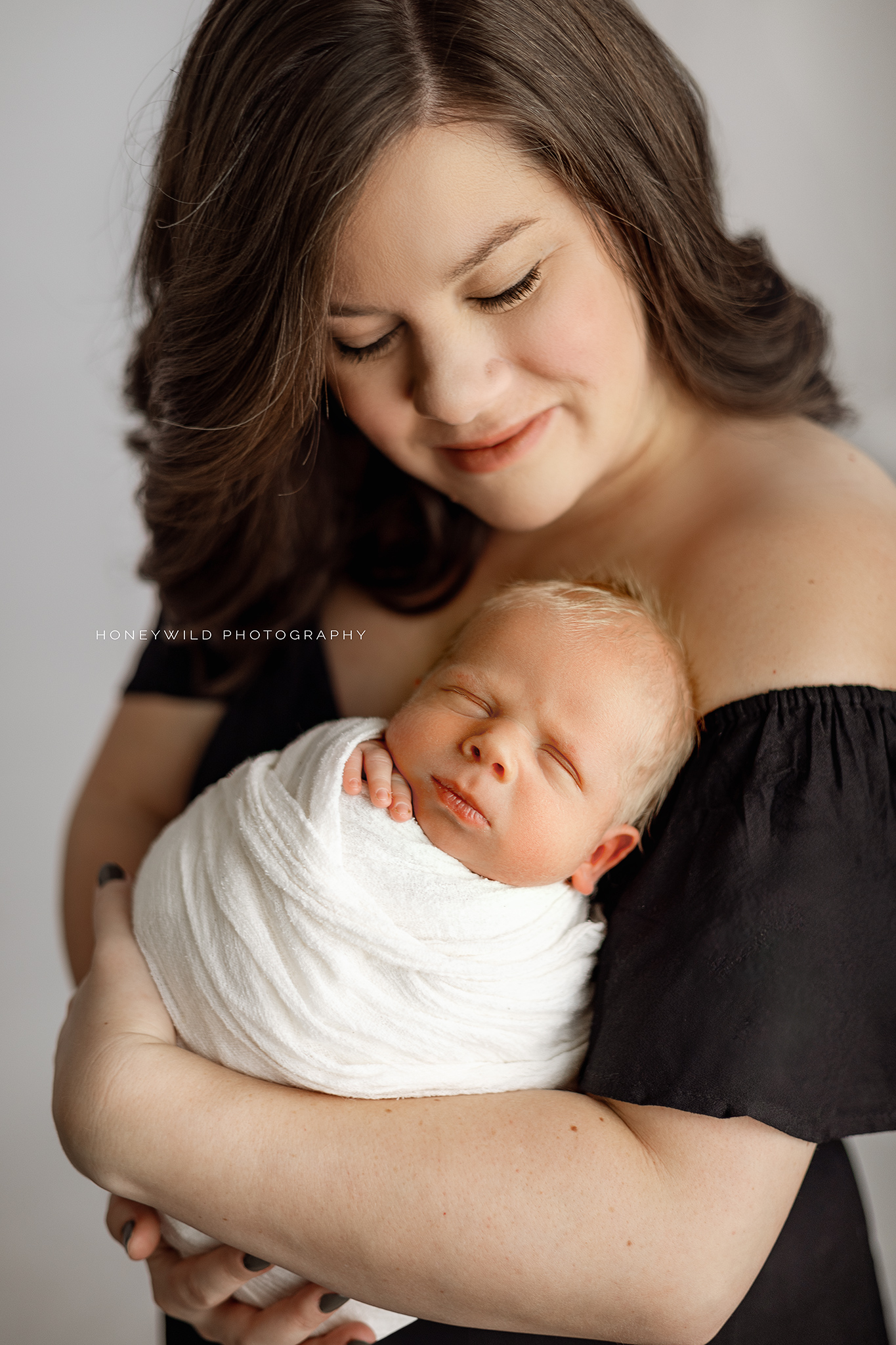 A mother holding her newborn close, captured at Honeywild Photography in Grand Rapids, MI.