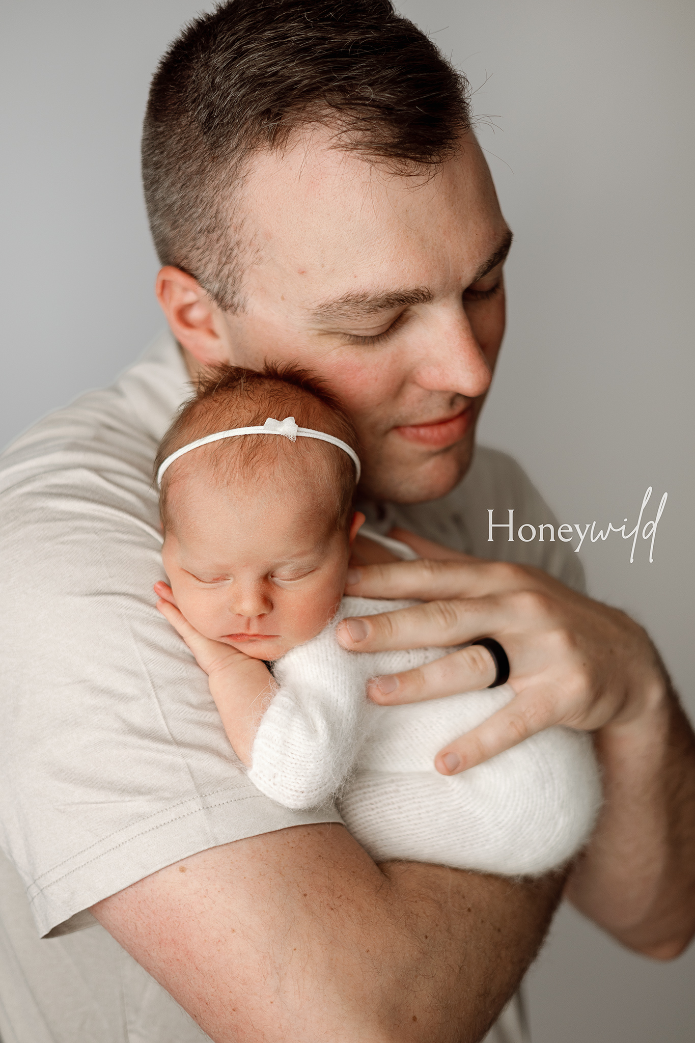 Grand Rapids newborn photographer capturing tender father-baby moments. Contact Honeywild Photography for timeless newborn photoshoots, including beautiful daddy and baby poses in Michigan