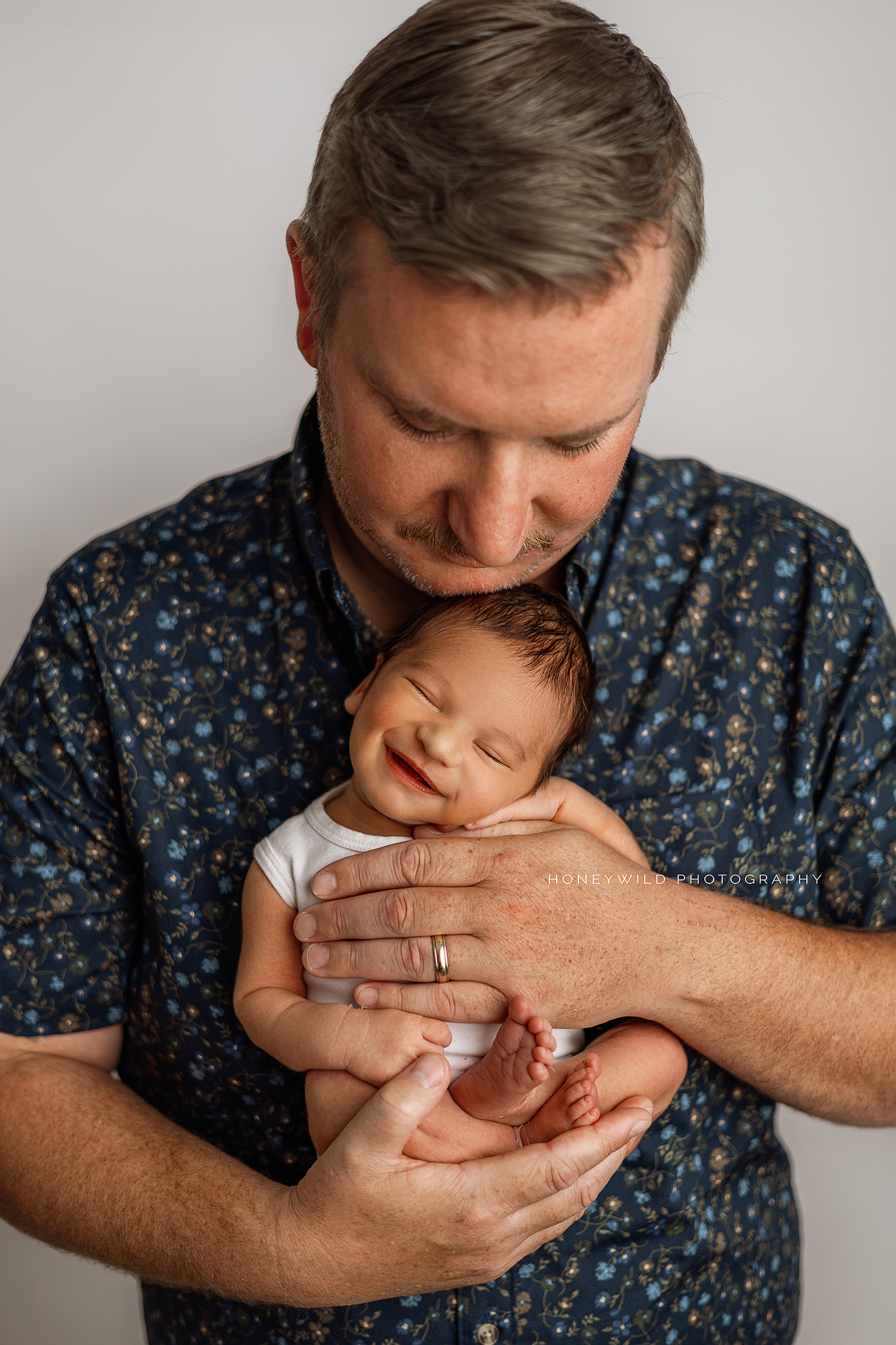 Grand Rapids newborn photographer capturing happy daddy and baby moments. Natural, authentic newborn sessions in West Michigan for new families.