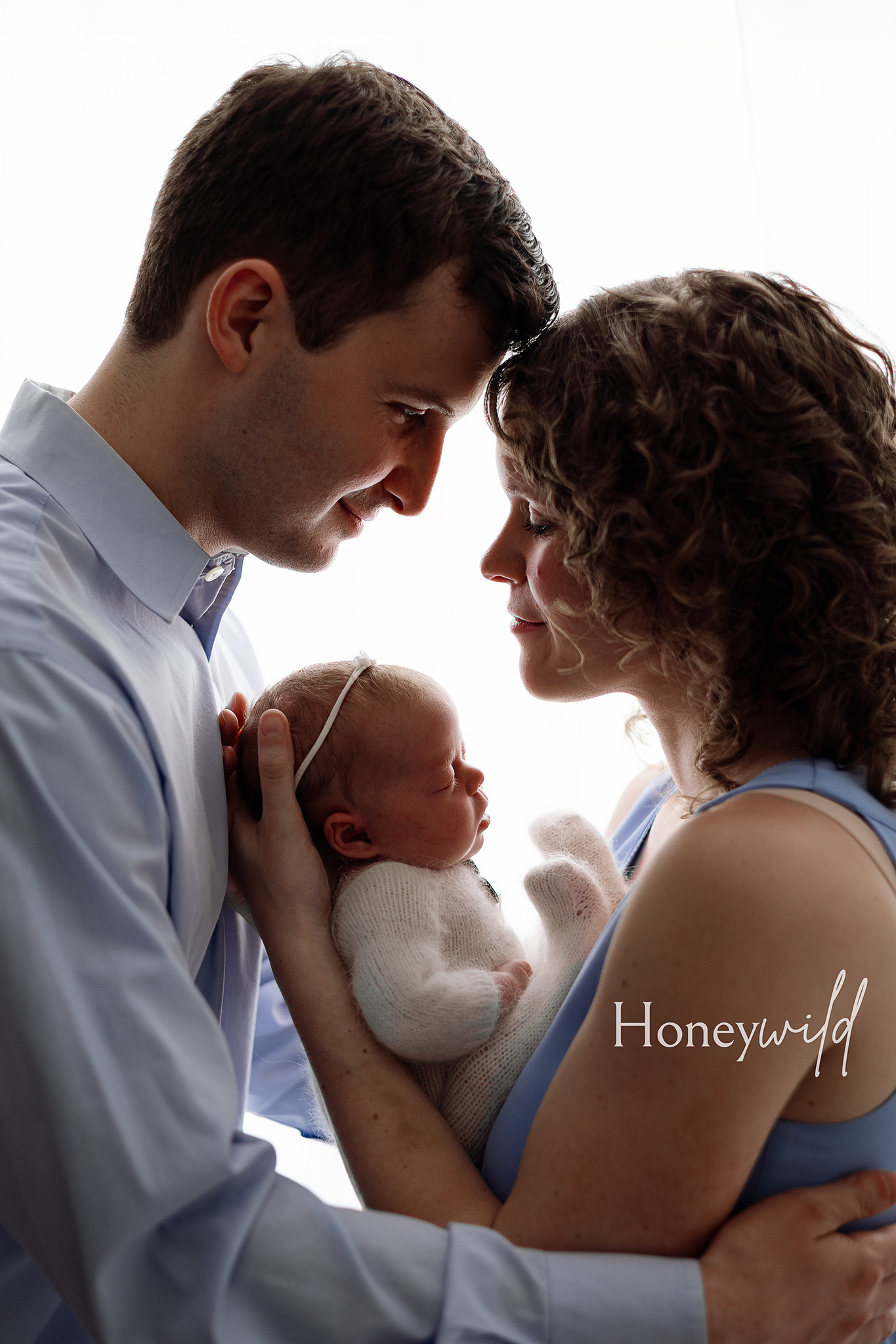 Grand Rapids newborn photography capturing intimate moments between new parents and their baby. Beautiful posed newborn photoshoots in West Michigan, creating timeless family art.