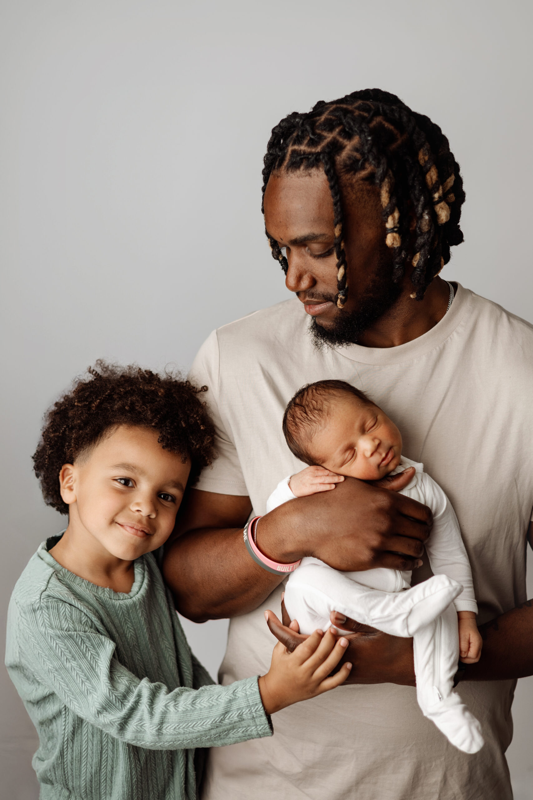 Grand Rapids family photographer showcasing the joy of a growing family, with a dad, older sibling, and newborn. Authentic and heartwarming family portraits in West Michigan.