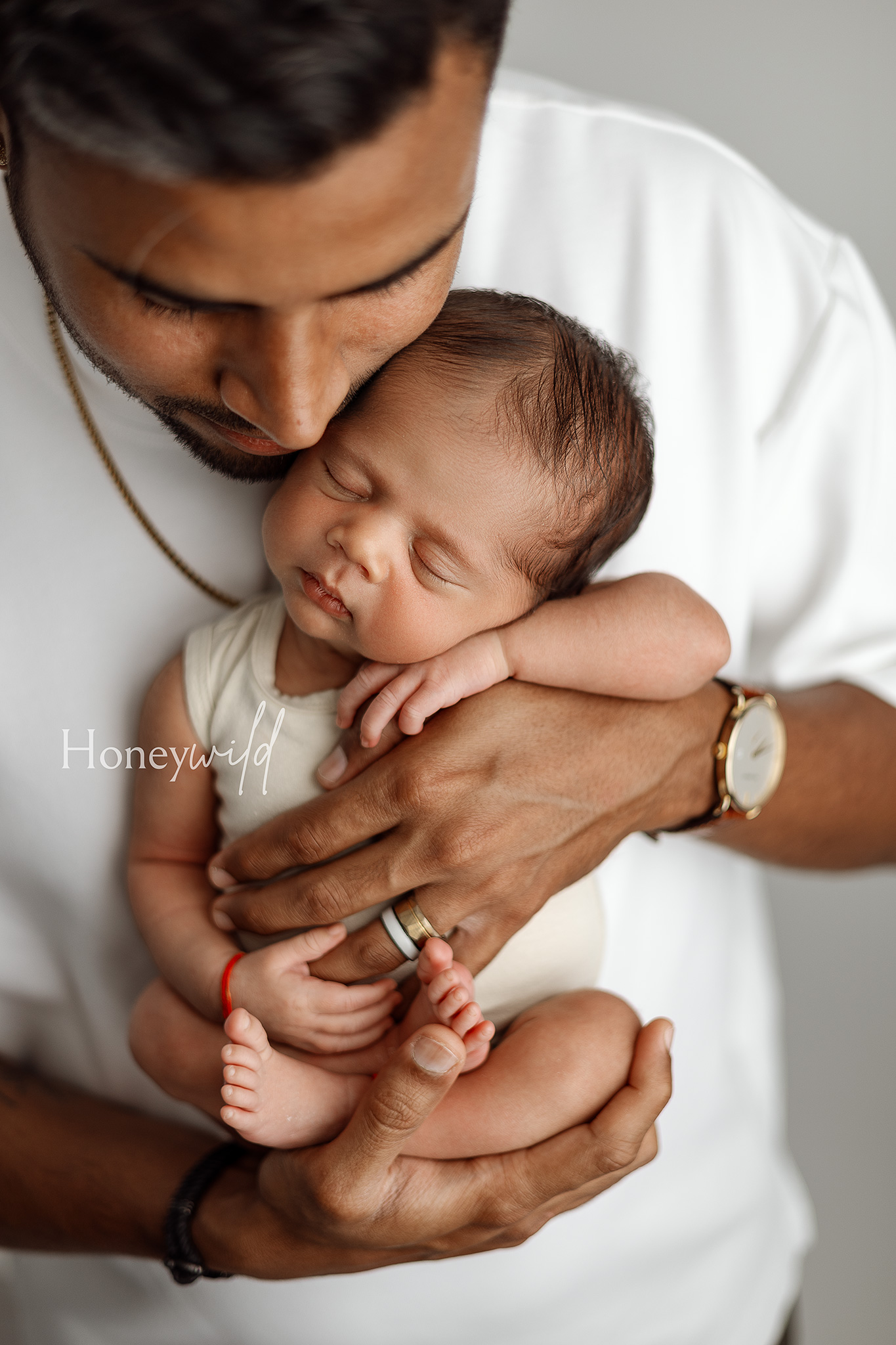 Soft, intimate newborn portrait of a father holding his sleeping baby during a Honeywild Photography session specializing in newborn photography in Grand Rapids, Michigan