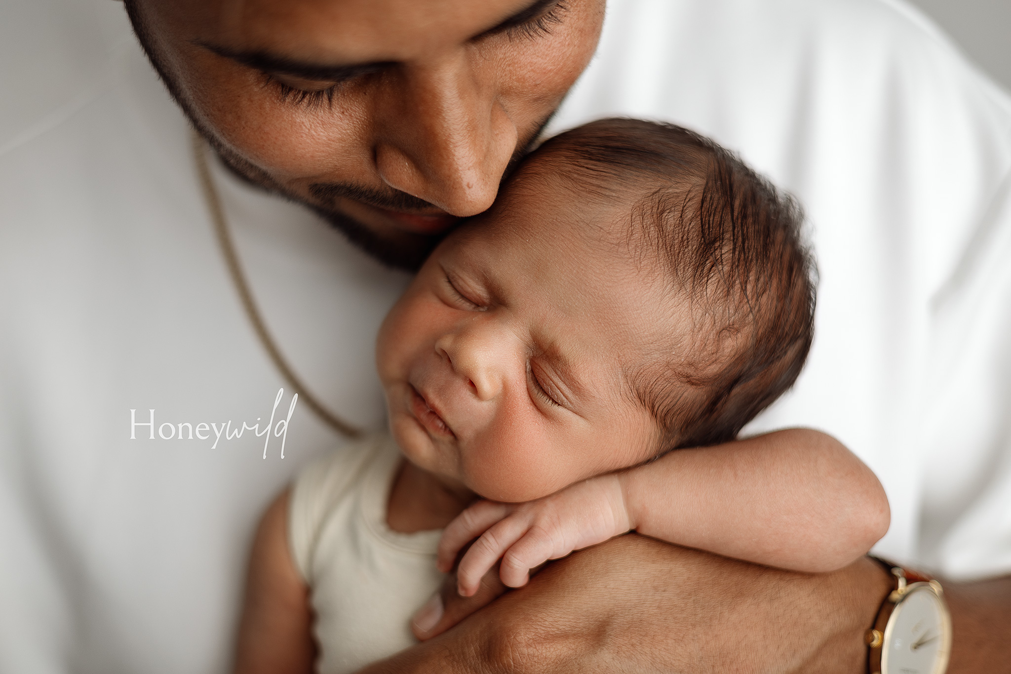 New father gently cradling his newborn in his arms during a Honeywild Photography session, capturing timeless newborn photography in Grand Rapids, MI