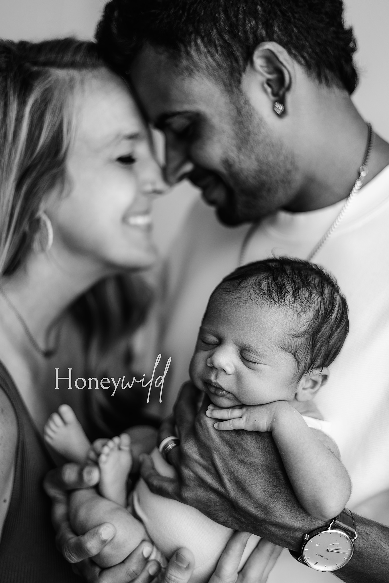 Emotional black and white newborn photo of parents cuddling their sleeping baby during a Honeywild Photography session offering newborn photography in Grand Rapids, MI