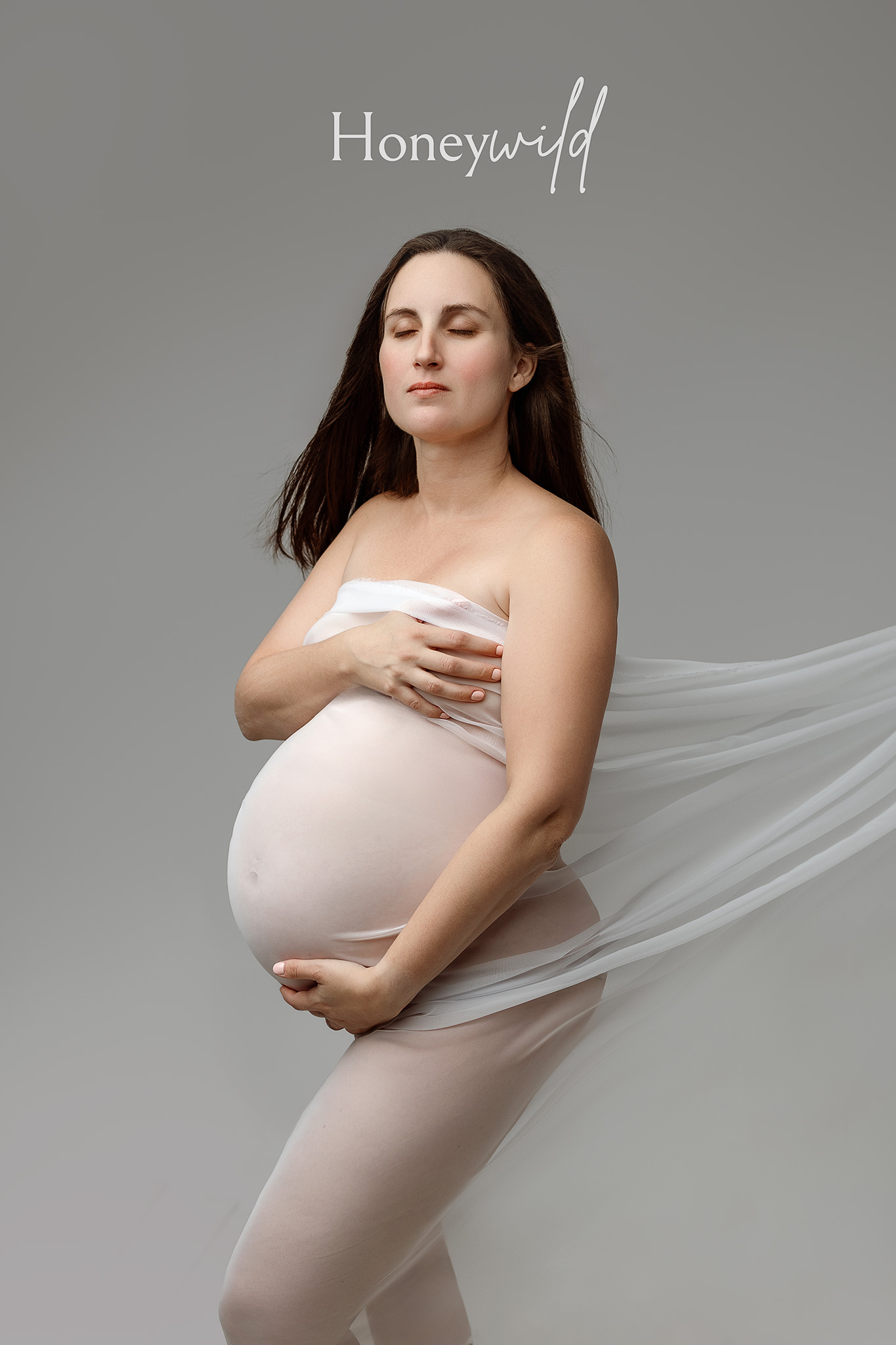 Close-up maternity portrait capturing a pregnant mother in profile with soft light and neutral studio background