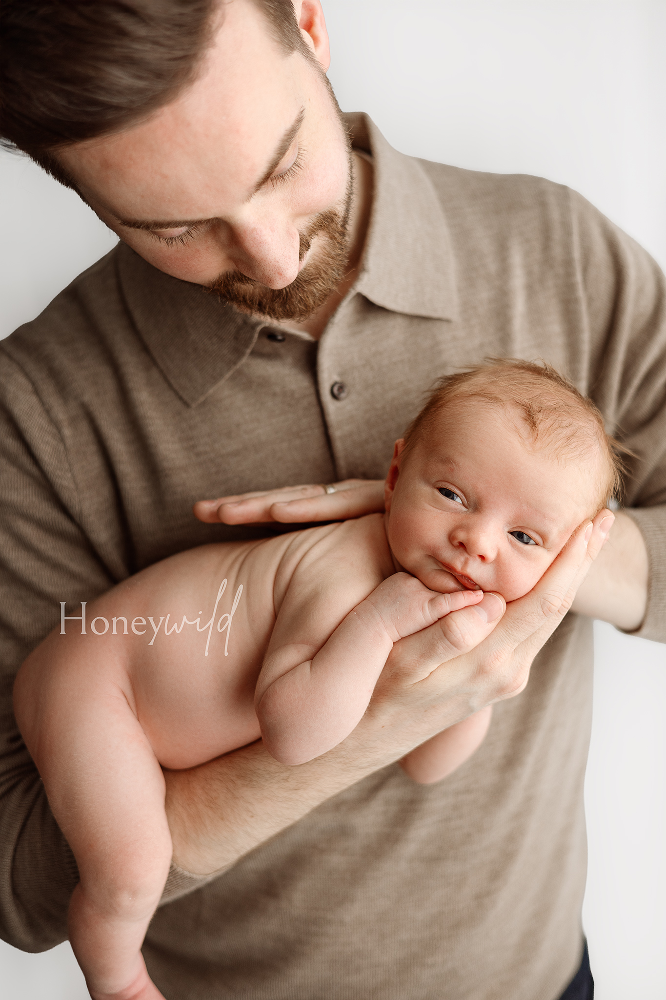 New father holding his newborn baby close during a peaceful, intentional newborn photography session