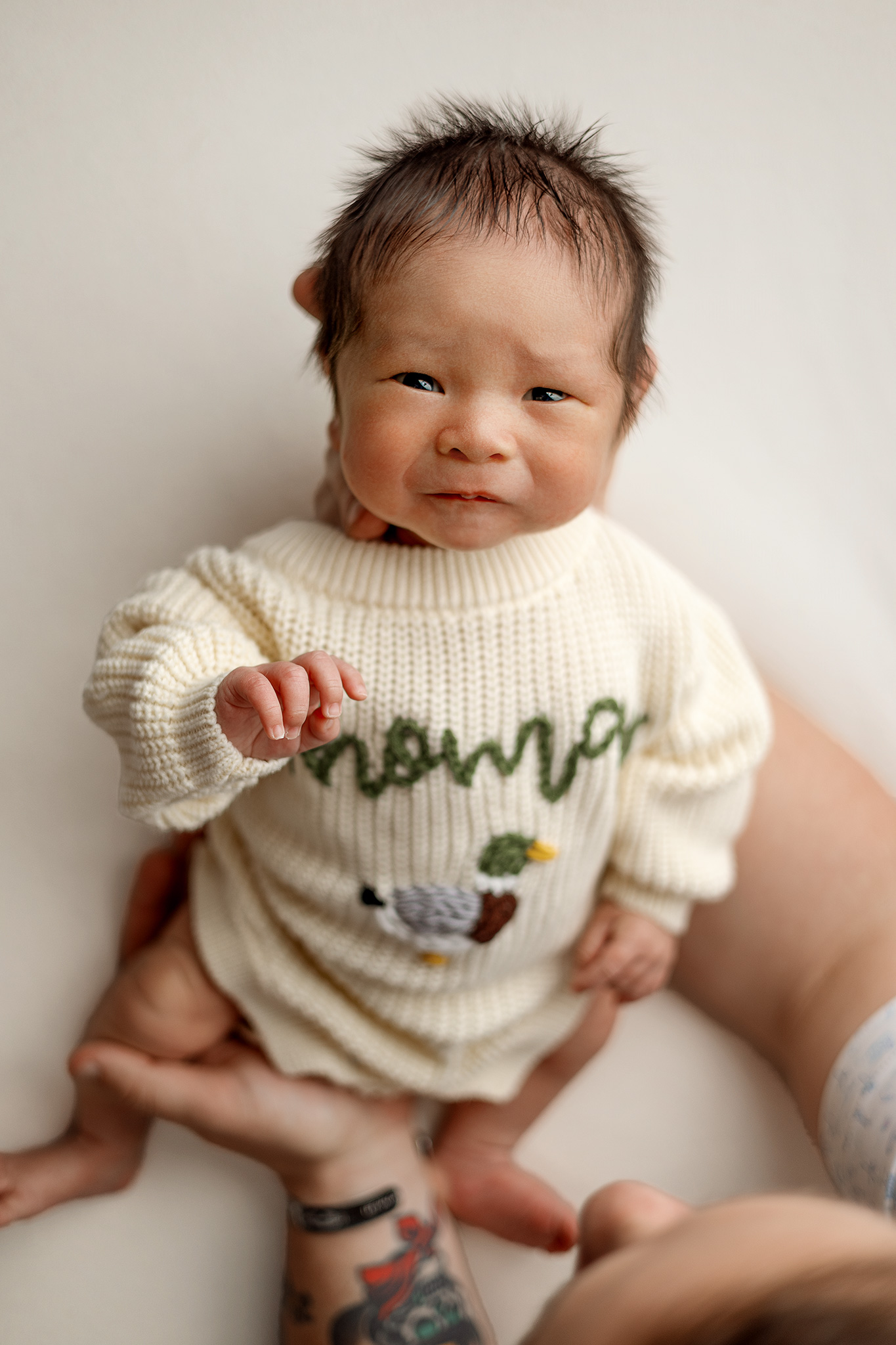 Awake newborn baby in a cream knit sweater photographed at Honeywild Photography studio in Grand Rapids Michigan