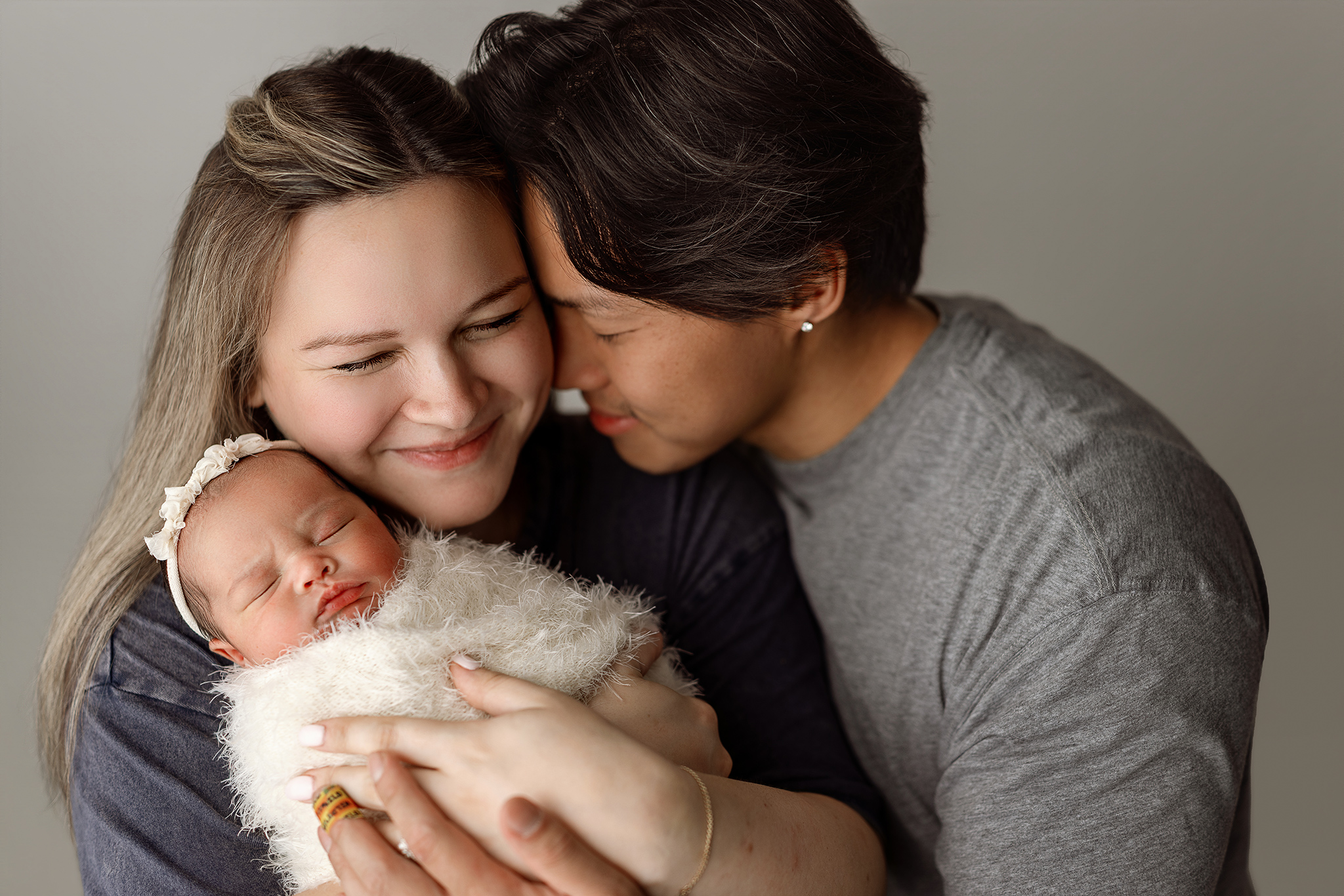 Parents holding their sleeping newborn baby during a studio newborn session at Honeywild Photography in Grand Rapids Michigan