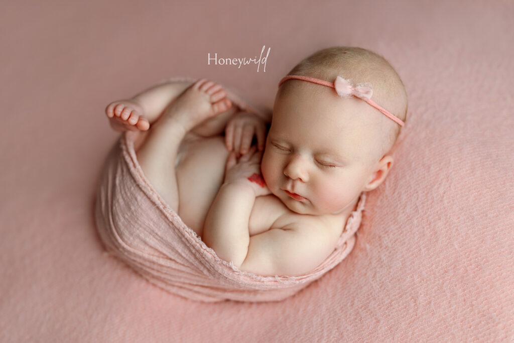 Newborn baby posed in a soft pink wrap at Honeywild Photography a studio newborn photographer in Grand Rapids and West Michigan