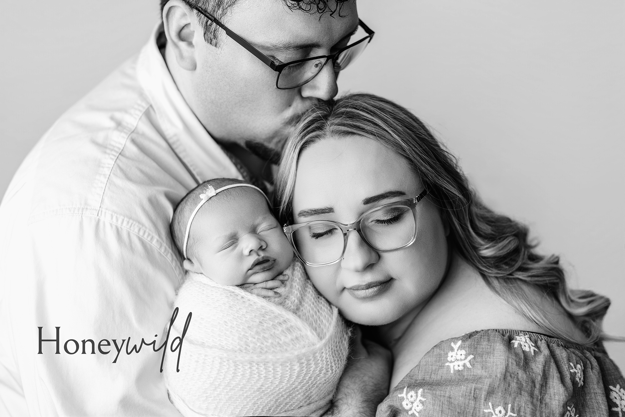 Grand Rapids newborn photography — parents holding sleeping newborn in black and white studio portrait