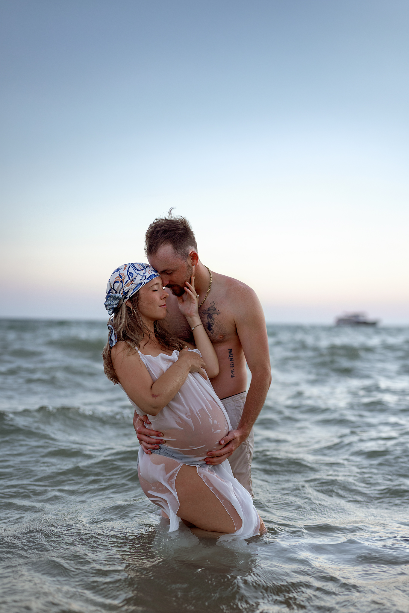 Couple embracing at sunset on Saugatuck beach, Michigan maternity photographer.