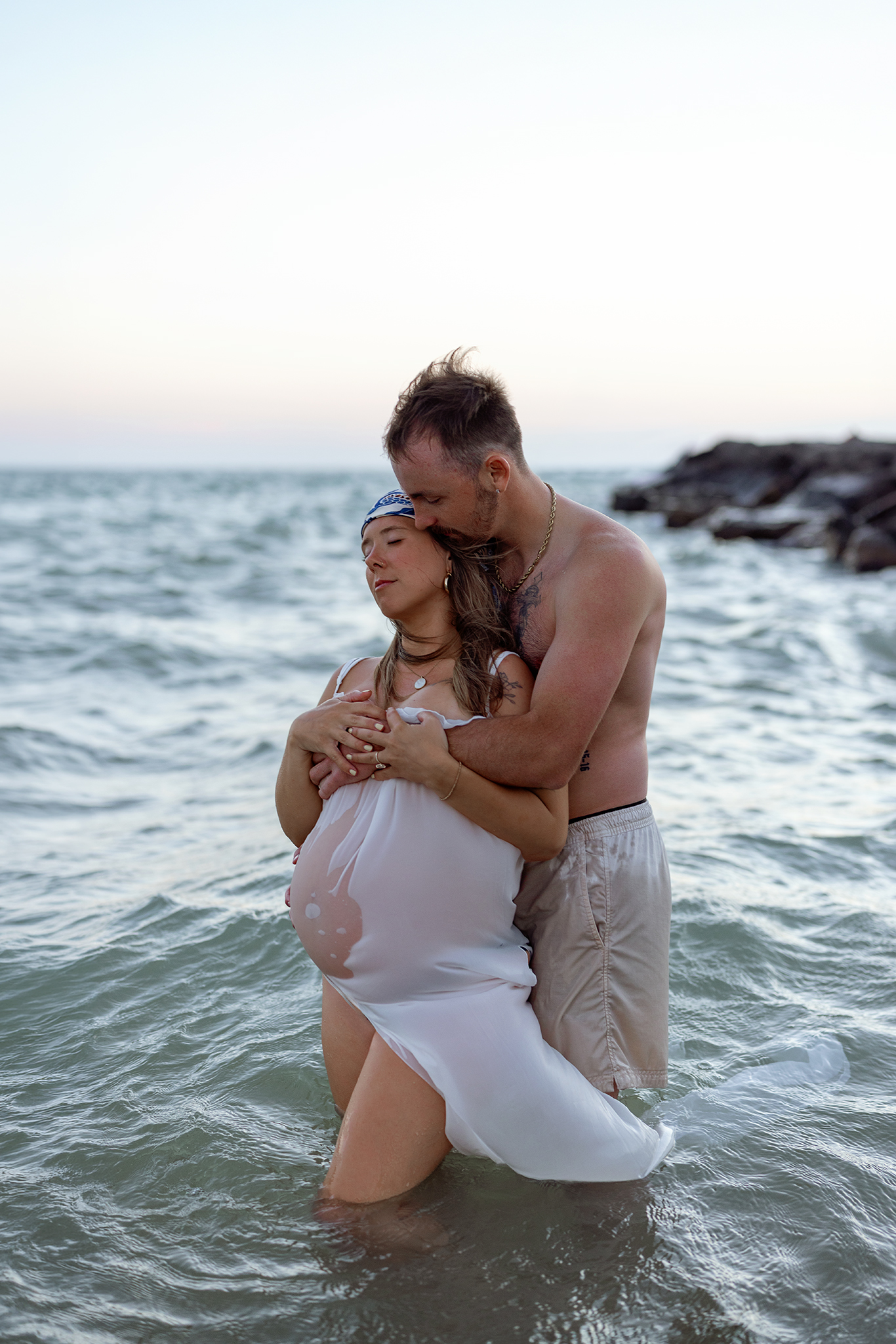 Couple embracing in Lake Michigan waves, Grand Rapids area maternity and couples photographer.
