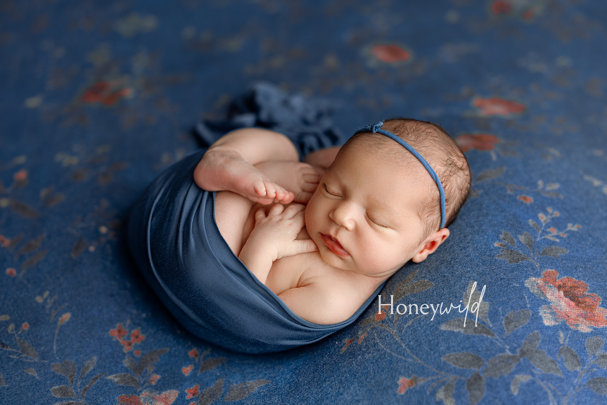 Grand Rapids newborn photography — swaddled baby sleeping on floral backdrop