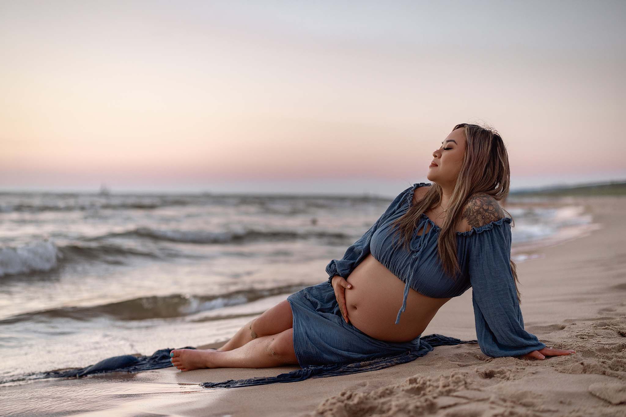 Michigan beach maternity session with mom in blue dress at sunset holding her. belly
