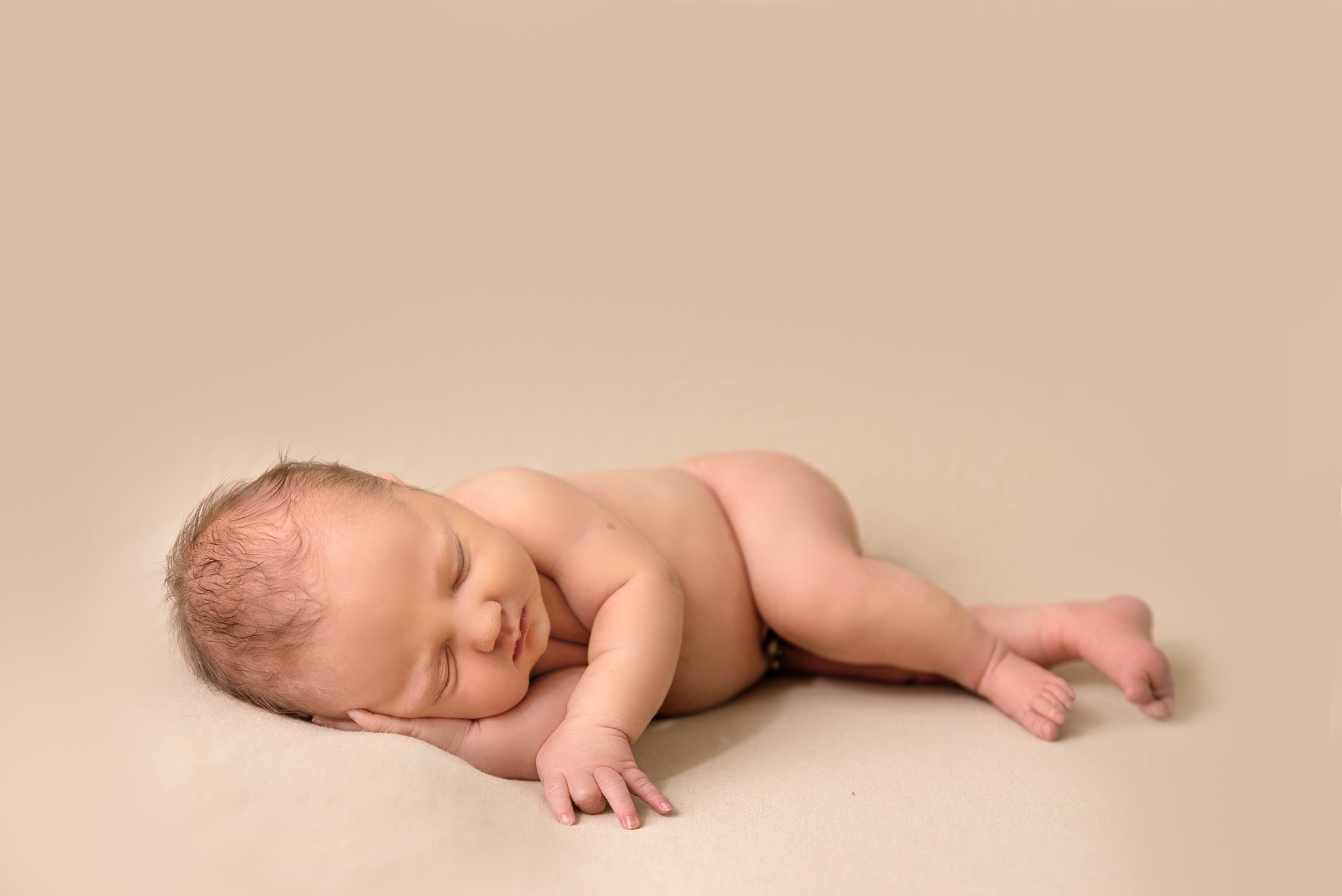 Grand Rapids Newborn baby sleeping on their side with head resting on hands, studio session in Grand Rapids